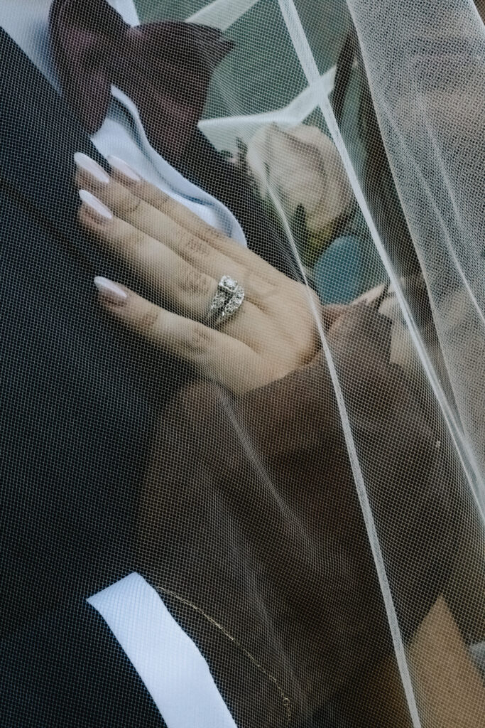 Close-up of bride’s hand with wedding ring under veil during an intimate elopement at Deer Cove in Azle Texas
