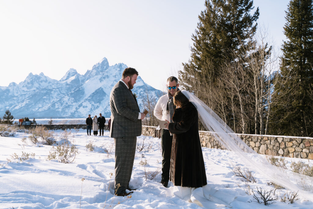 Couple exchanging vows during a snowy elopement ceremony in Grand Teton National Park Wyoming with mountain views