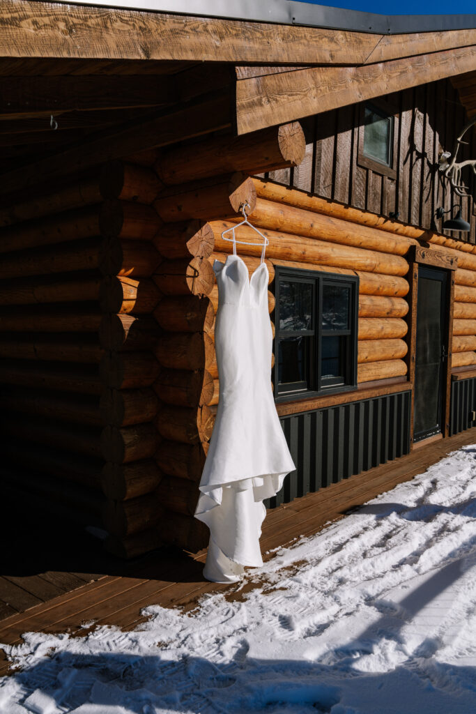 Wedding dress hanging outside a rustic log cabin during a Grand Teton National Park elopement in Wyoming