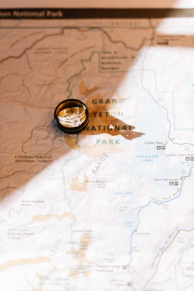 Wedding rings on a map of Grand Teton National Park representing a Wyoming elopement photographer capturing intimate wedding details